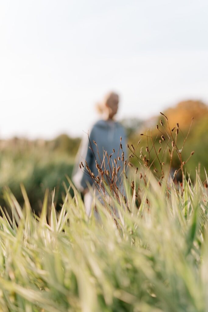 Woman walking through a sunlit meadow of tall grasses